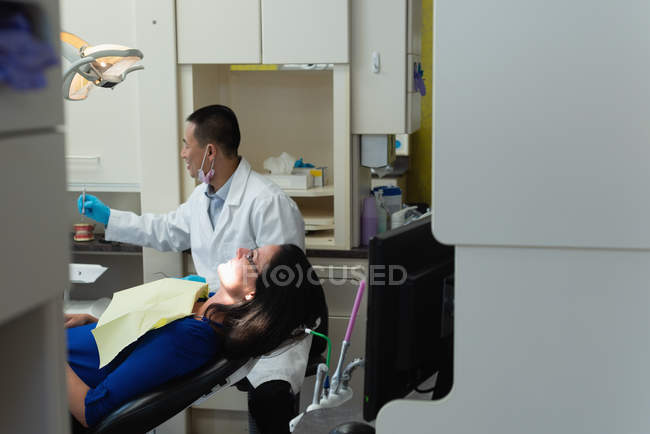 Odontólogo masculino examinando a una paciente en la clínica - foto de stock