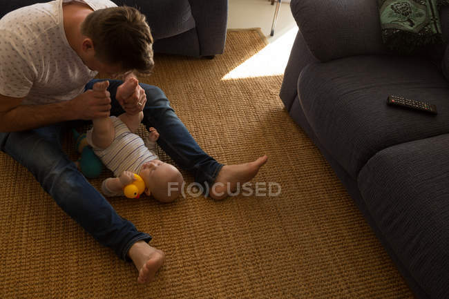 Padre che gioca con il suo bambino in salotto a casa — Foto stock