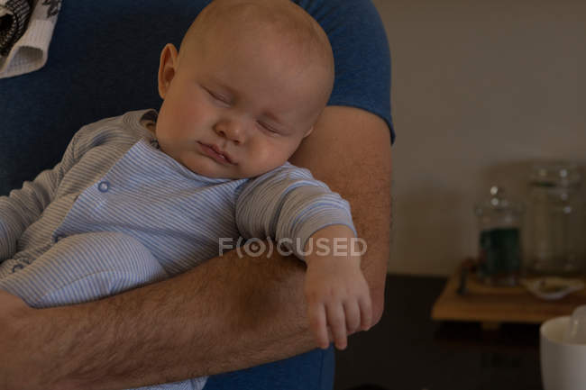 Bébé garçon dormir dans son père bras à la maison — Photo de stock