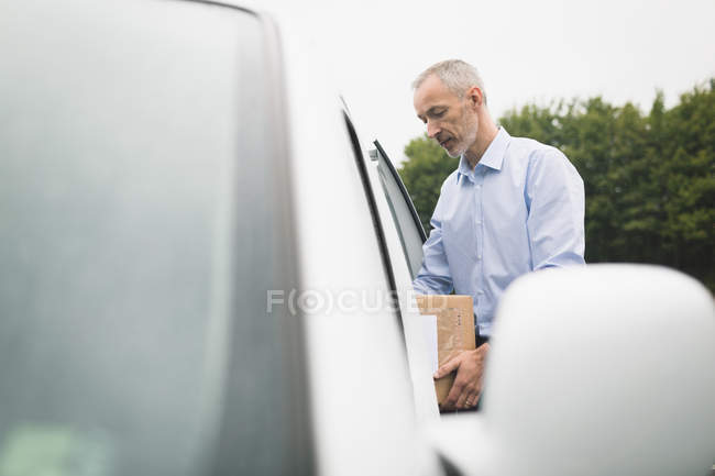 Чоловік-доставка розвантажує посилку з фургона на сонячний день — стокове фото