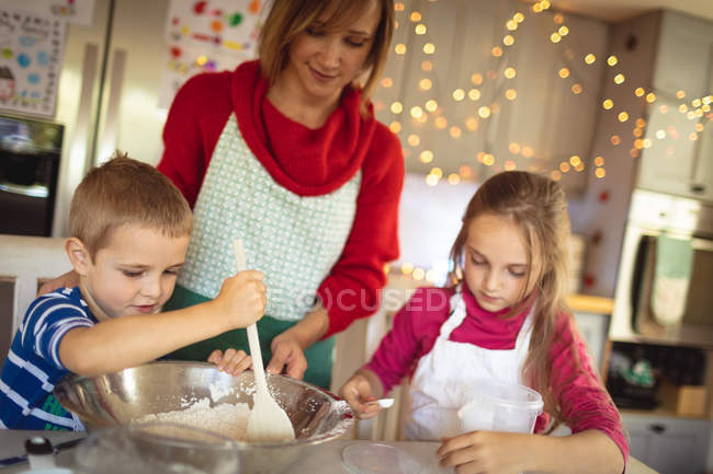Mère et enfants faisant des biscuits de Noël dans la cuisine à la maison — Photo de stock