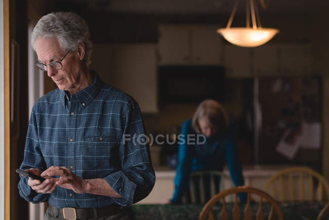 Homem sênior usando telefone celular em casa — Fotografia de Stock