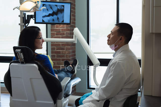 Dentista masculino que interactúa con el paciente en la clínica - foto de stock