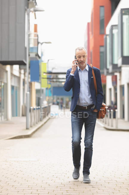 Homme d'affaires parlant sur un téléphone portable tout en marchant dans la ville — Photo de stock
