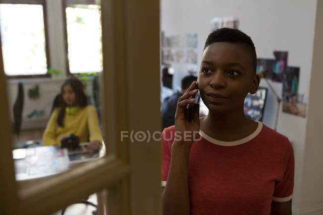 Молодая женщина-руководитель разговаривает по мобильному телефону в офисе — стоковое фото