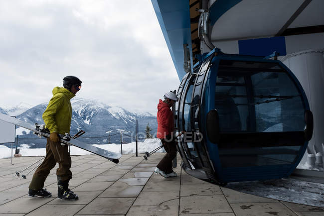 Casal com skiboard entrando no teleférico durante o inverno — Fotografia de Stock