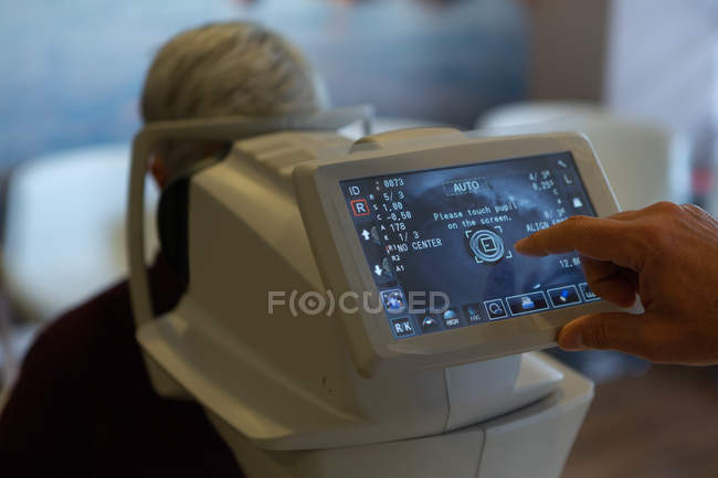 Nahaufnahme des Augenoptikers bei der Untersuchung von Patientenaugen mit Autorefraktoren in der Klinik — Stockfoto