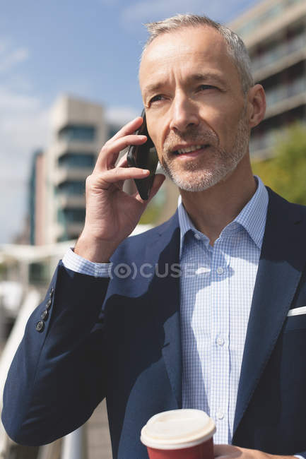 Primer plano del hombre de negocios hablando por teléfono móvil en la ciudad - foto de stock