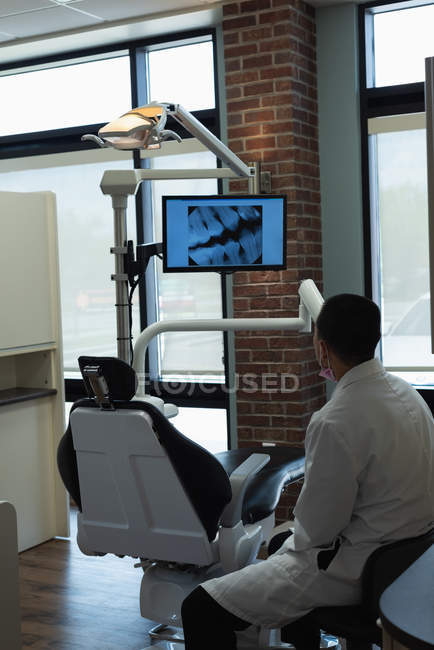 Vista posteriore del dentista maschio che guarda lo schermo a raggi X in clinica — Foto stock
