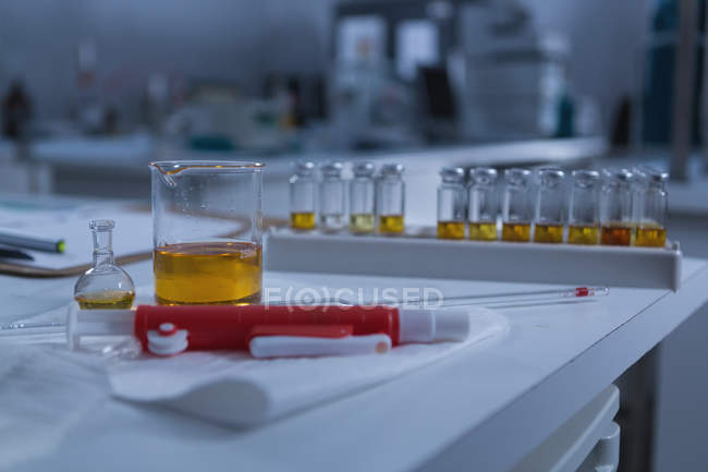 Close-up of beaker, test tube rack and clipboard on table — Stock Photo