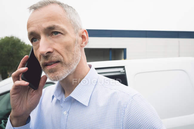 Close-up de homem de entrega falando no telefone celular no armazém — Fotografia de Stock