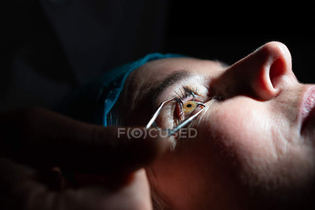 Крупный план оптометриста, осматривающего глаза пациента с помощью оборудования для проверки зрения в клинике — стоковое фото