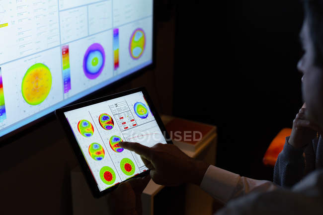 Optometrista explica informe de vista sobre tableta digital en clínica - foto de stock