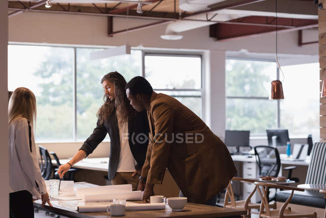 Бізнесмени обговорюють креслення в офісі — стокове фото