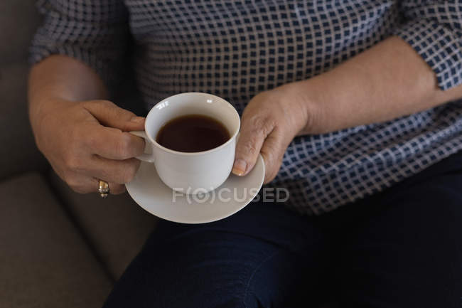 Seniorin trinkt schwarzen Kaffee im heimischen Wohnzimmer — Stockfoto