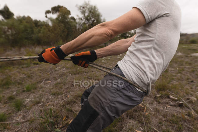 Mid section lumberjack pulling rope in the forest — Stock Photo