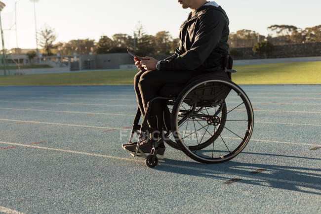 Vista lateral del atlético discapacitado utilizando tableta digital en el lugar de deportes - foto de stock