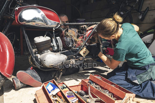 Mechaniker und Mechanikerinnen reparieren Motorrad in Werkstatt — Stockfoto