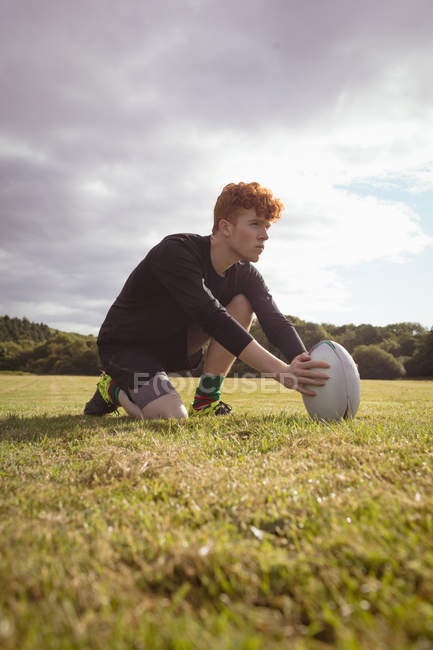 Joueur de rugby plaçant la balle de rugby sur le terrain par une journée ensoleillée — Photo de stock