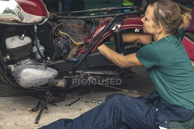 Gros plan de la réparation mécanique féminine moto dans le garage — Photo de stock