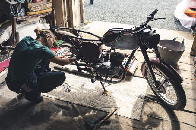 Feminino mecânico reparação de moto na garagem — Fotografia de Stock