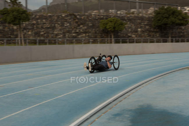 Atleta disabile che corre in sedia a rotelle su una pista da corsa — Foto stock