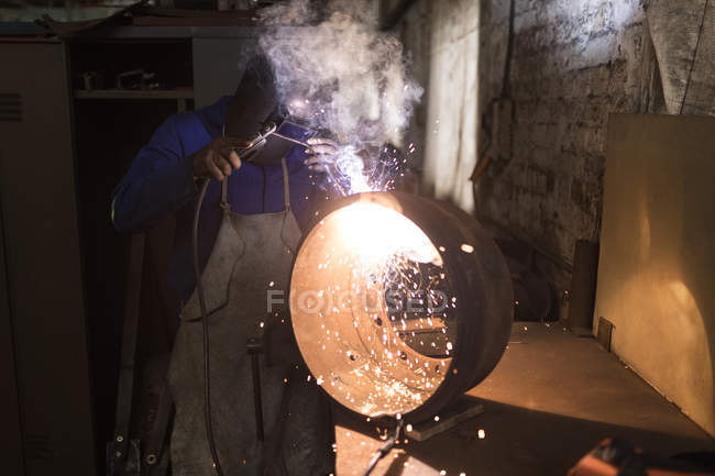 Внимательный кузнец с помощью сварочной горелки в мастерской — стоковое фото