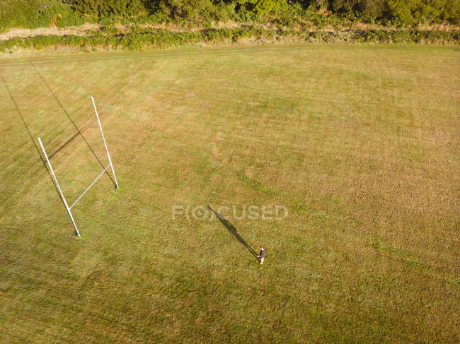 Jugador de rugby mirando el poste de gol en el campo en un día soleado - foto de stock