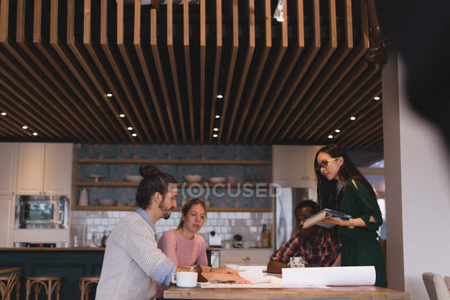 Four business people discussing blueprints in the office — Stock Photo