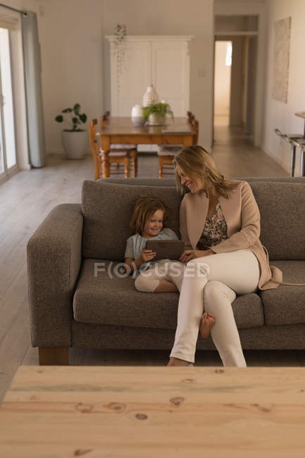Mãe e filha usando tablet digital na sala de estar em casa — Fotografia de Stock