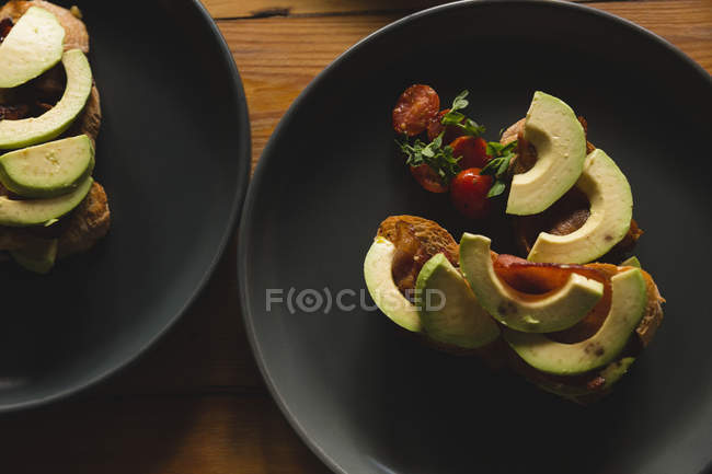 Aguacate en rodajas y cereza servidos en plato en la cafetería - foto de stock