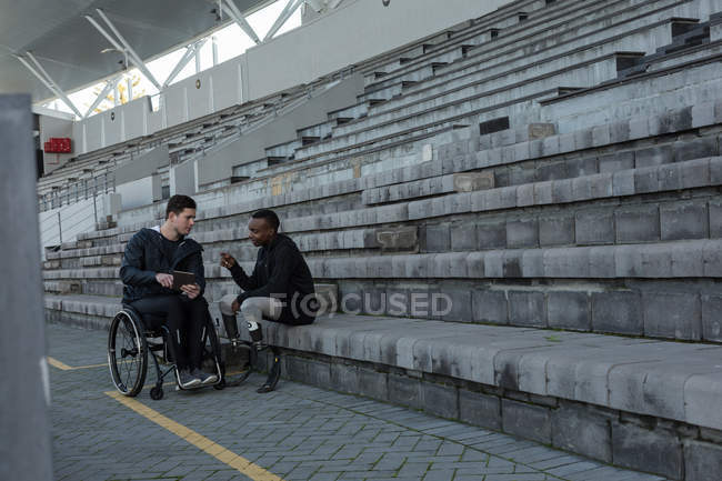 Dos atletas discapacitados discutiendo sobre tableta digital en el lugar de los deportes - foto de stock