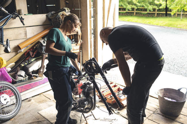 Чоловічий і жіночий mechanicians, ремонт мотоцикл в ремонт гаража — стокове фото