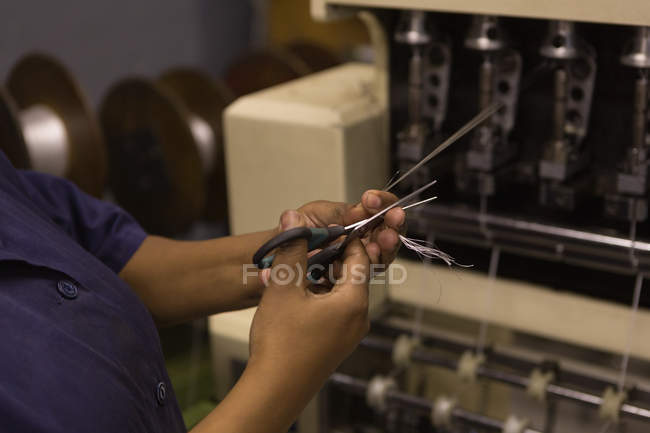 Mid section of worker cutting fibre in rope making industry — Stock Photo