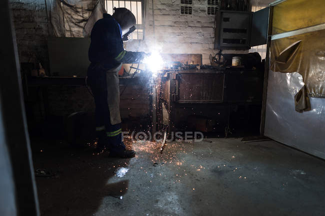 Side view of blacksmith using a welding torch in workshop — Stock Photo