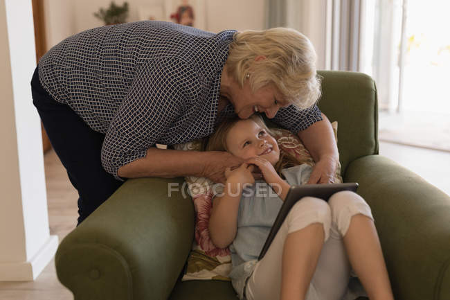 Бабушка и внучка используют цифровые планшеты в гостиной дома — стоковое фото