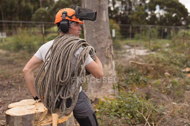 Rear view of lumberjack relaxing on tree stump in the forest — Stock Photo