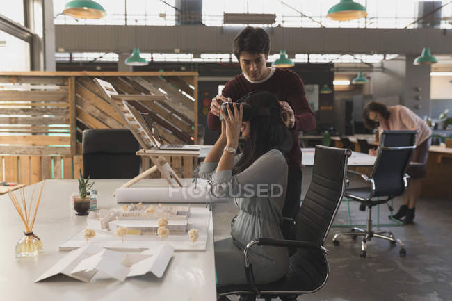 Executives using virtual reality headset at table in office — Stock Photo