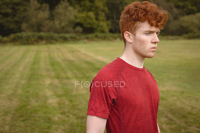 Thoughtful football player standing in the field — Stock Photo