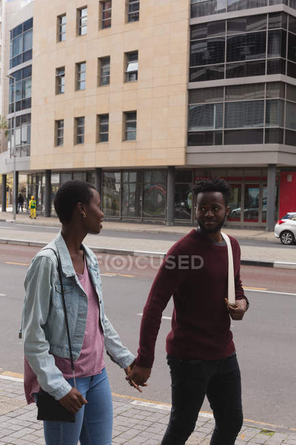 Романтическая пара, держащаяся за руки на городской улице — стоковое фото