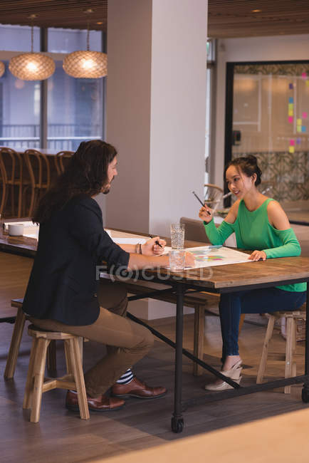 Businessman and businesswoman discussing blueprints in the office — Stock Photo