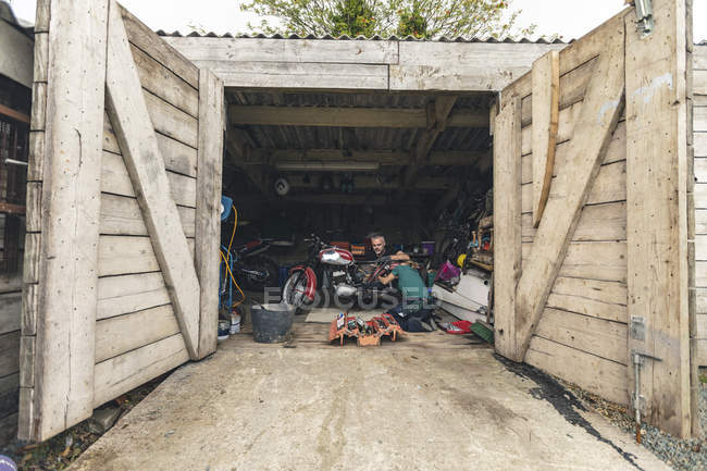 Чоловічі та жіночі механіки ремонтують мотоцикл у ремонтному гаражі — стокове фото