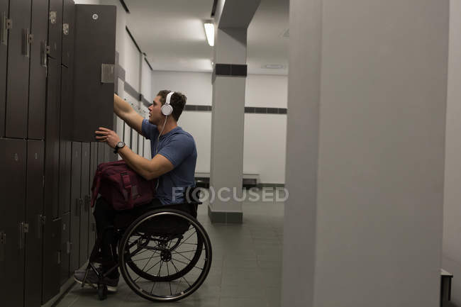 Homem com deficiência ouvindo música em fones de ouvido no vestiário — Fotografia de Stock