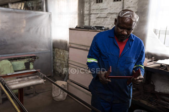 Male blacksmith holding metal equipment in workshop — Stock Photo
