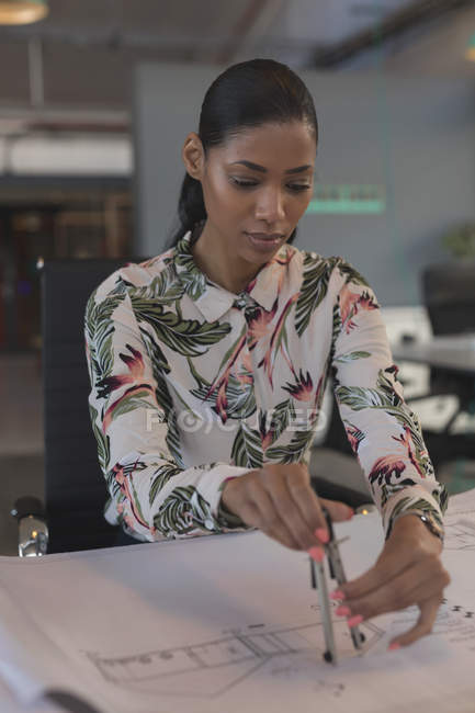 Dibujo ejecutivo femenino sobre plano en el escritorio en la oficina - foto de stock