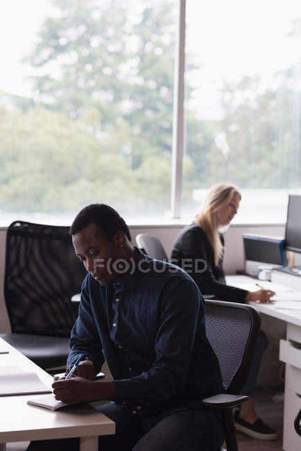 Empresario y empresaria concentrados que trabajan en la oficina - foto de stock