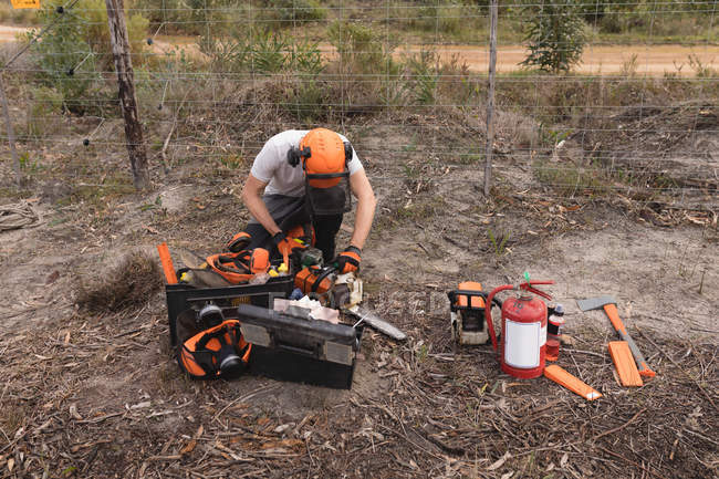 Lumberjack usando máquina de motosserra na floresta — Fotografia de Stock