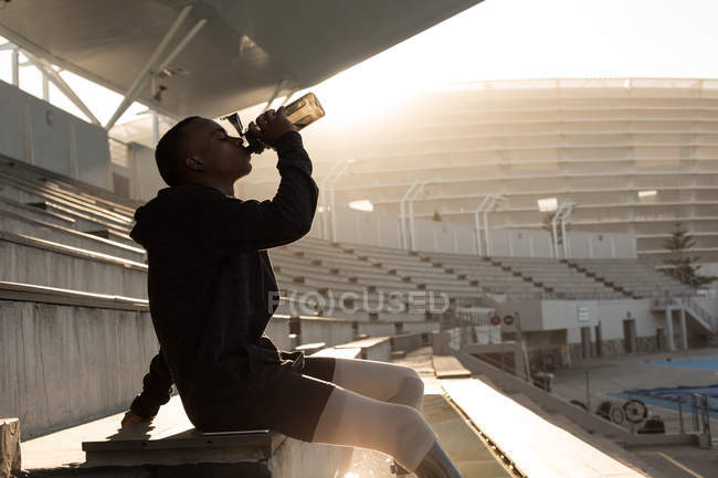 Seitenansicht behinderter Sportler trinkt Wasser an Sportstätte — Stockfoto