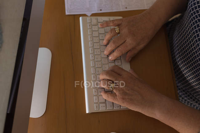 Mid section of senior woman working on computer at home — Stock Photo