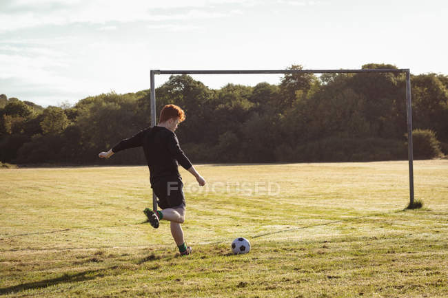 Giocatore di calcio calci calcio in campo in una giornata di sole — Foto stock